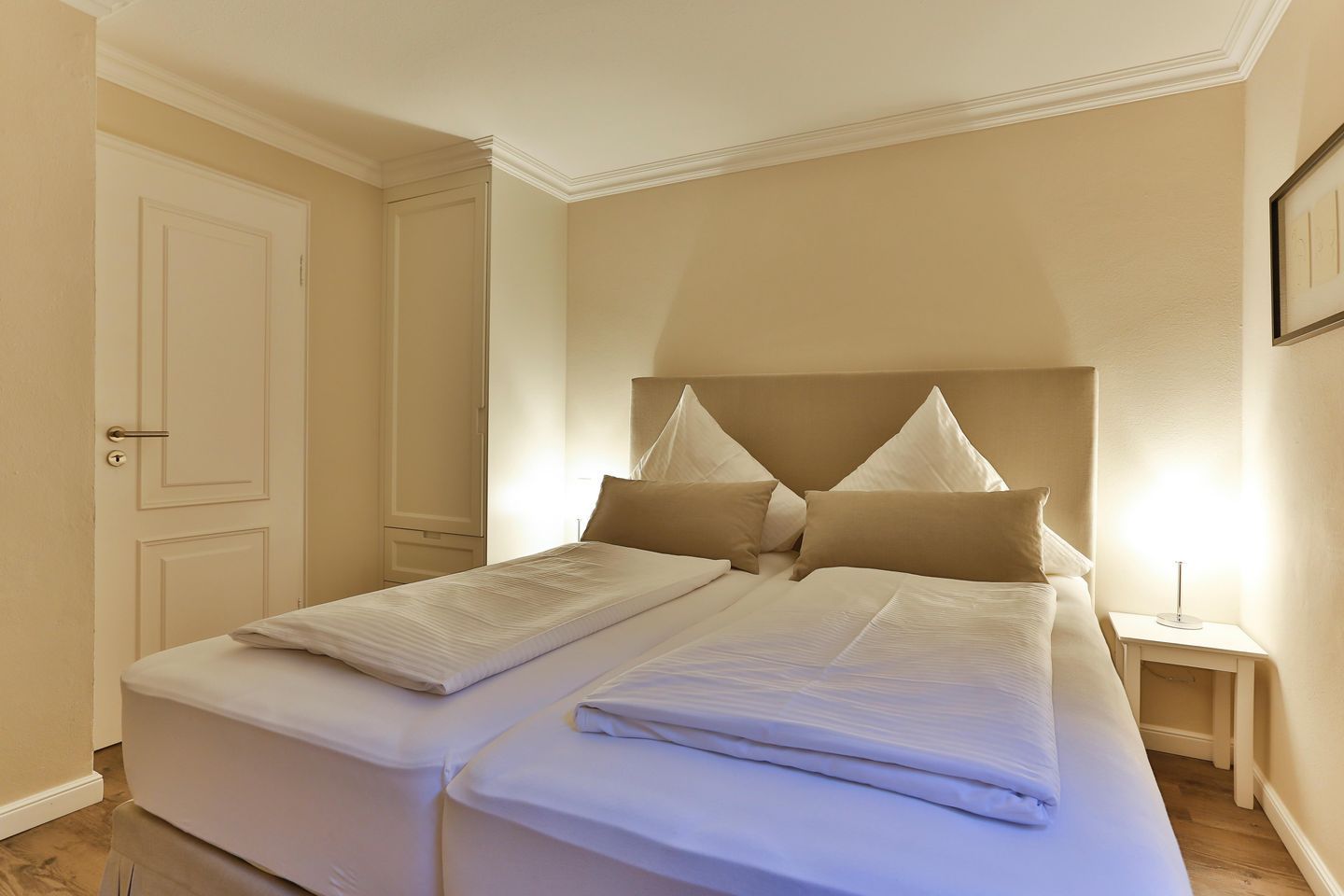 A double bed with a headboard, two bedside tables, and a door.