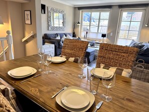 A dining area with a wooden table set for four, surrounded by wicker chairs. - Apartment Pebbles - 3-room apartment for 4 persons with terrace, parking space, (Sylt)