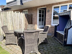 A patio area with wicker furniture, a glass table, and a blue cushioned bench. - Apartment Pebbles - 3-room apartment for 4 persons with terrace, parking space, (Sylt)