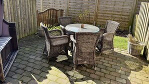 A patio with wicker furniture, a round table, and a wooden fence.