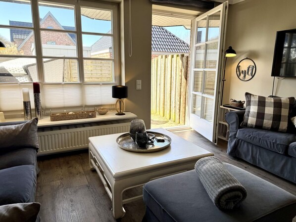 A cozy living room with a sofa, a coffee table, and a window overlooking a backyard.