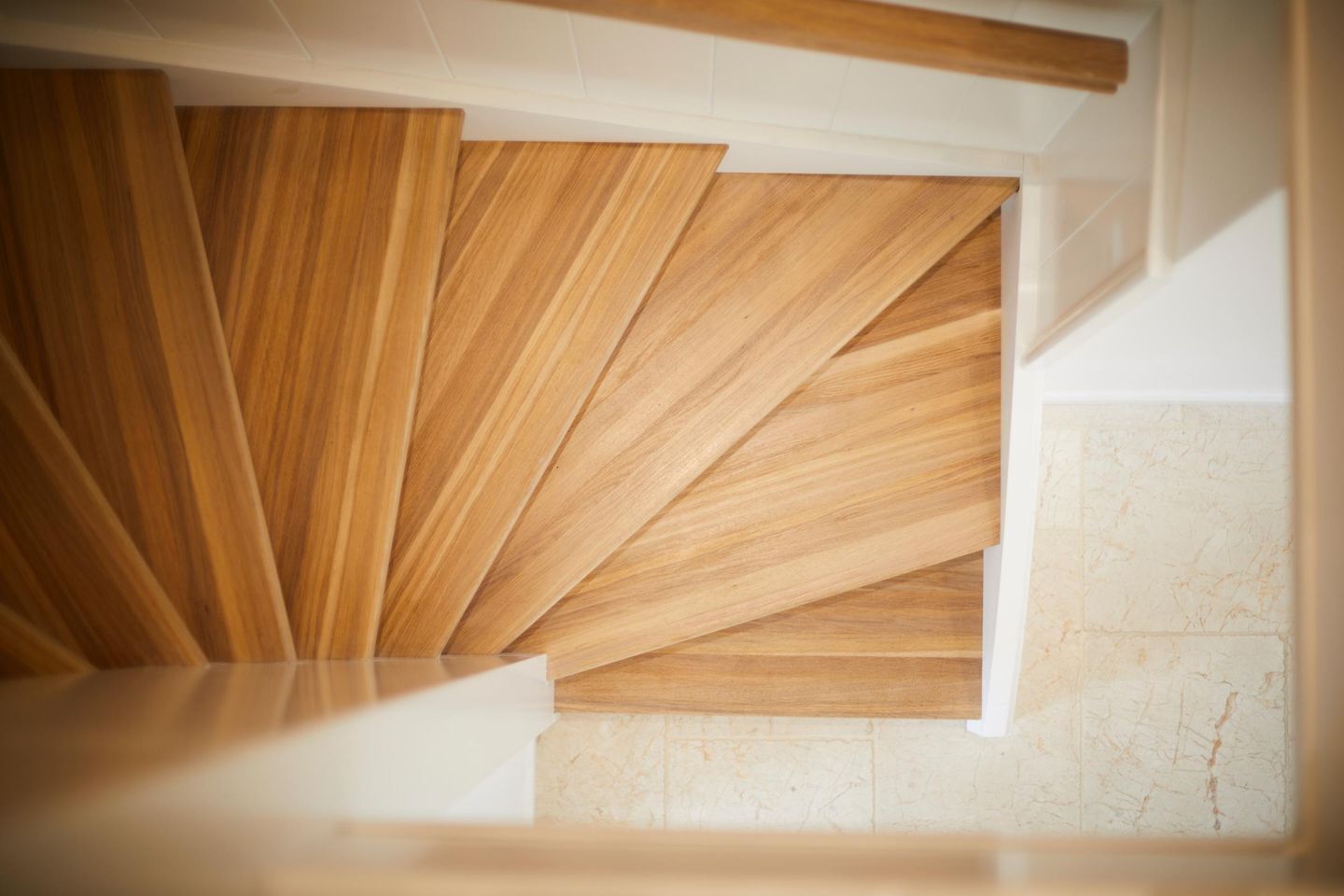 A modern staircase with wooden panels and a marble floor.