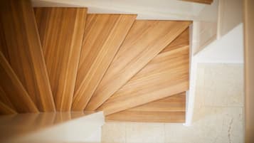 A modern staircase with wooden panels and a marble floor.