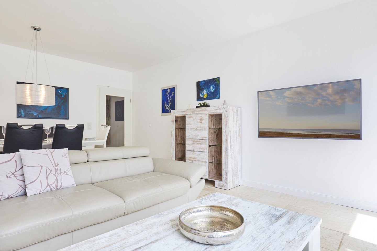 A modern living room with a sofa, a coffee table, and a dining area with chairs and a table.