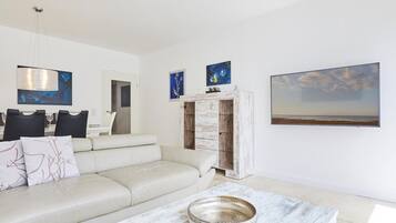 A modern living room with a sofa, a coffee table, and a dining area with chairs and a table.