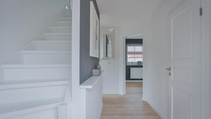 Ein modernes Interieur mit einer Treppe, weißen Wänden und Blick in einen Küchenbereich.