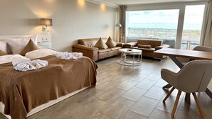 Une chambre d’hôtel avec un lit, deux canapés, une table à manger et une vue sur la ville.