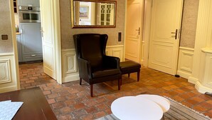 A room with a brick floor, a black leather chair, a white table, and a door with a mirror above it. - Kiebitz - Beautiful 2-room apartment with terrace, parking space, WLAN. Pets (Sylt)