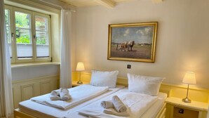 A hotel room with two beds, a painting on the wall, and a window with curtains. - Kiebitz - Beautiful 2-room apartment with terrace, parking space, WLAN. Pets (Sylt)