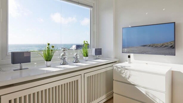 A modern bathroom with a large window, a flat-screen TV, and a radiator. - Sea view I - Modern apartment, balcony with sea view, parking space, WLAN. (Sylt)