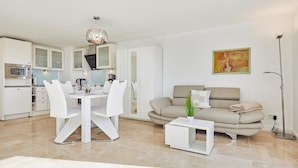 A modern living room with a dining area, a sofa, and a coffee table. - Sea view I - Modern apartment, balcony with sea view, parking space, WLAN. (Sylt)