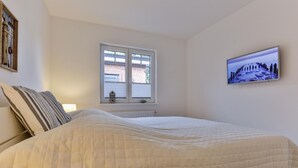 Um quarto com uma cama, uma janela e um quadro na parede.