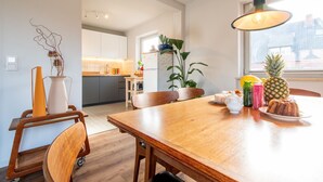Eine moderne Küche mit weißen Schränken, einem Holztisch und einer Pendelleuchte.