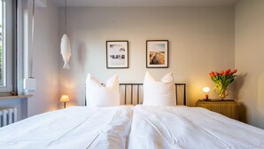 Ein Hotelzimmer mit einem großen Bett, zwei gerahmten Bildern an der Wand, einer Nachttischlampe und einer Vase mit Blumen.