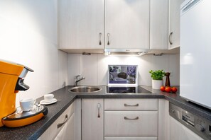 A modern kitchen with white cabinets, a stainless steel sink, and a built-in oven. - Strandgeflüster - Comfortable apartment near the beach, with a west-facing balcony, car (Sylt)