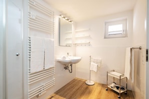 Un baño moderno con lavamanos, espejo y toallero blancos.