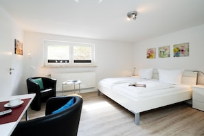 Una habitación de hotel moderna con una cama, un escritorio, una silla y una mesita.