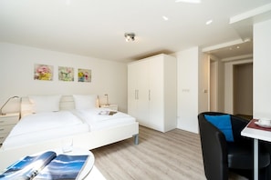 A modern hotel room with a bed, bedside tables, a desk, and a wardrobe. - Haus Sundermann - Fantastic apartment under thatch for 5 people, sea view, (List)