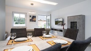 A modern dining area with a table set for four, featuring a neutral color palette and contemporary furnishings. - Albatros Ground Floor - Modern 3-room apartment for 4 people with a terrace, garden, and parking space (Sylt)
