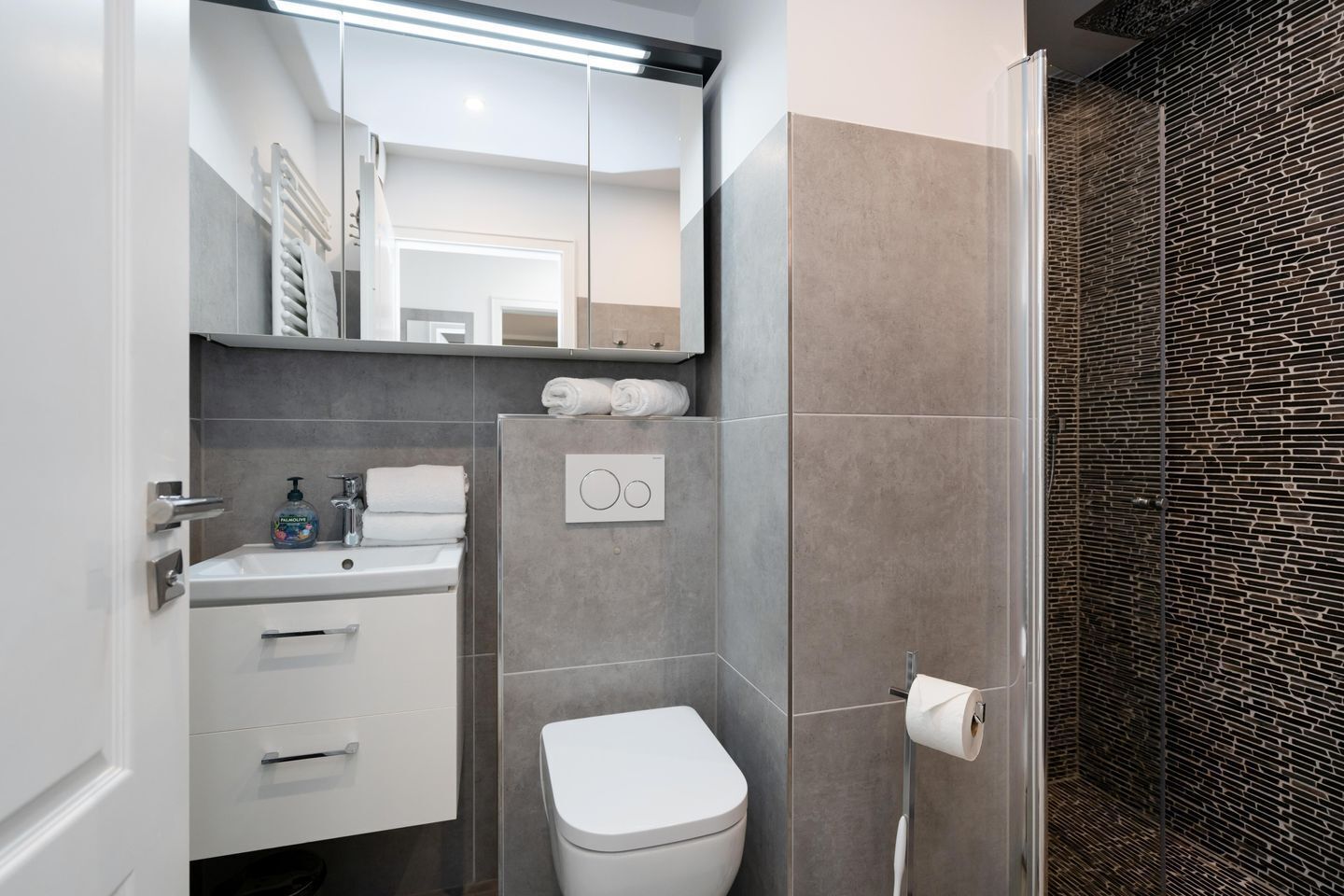 A modern bathroom with a toilet, sink, and mirror.
