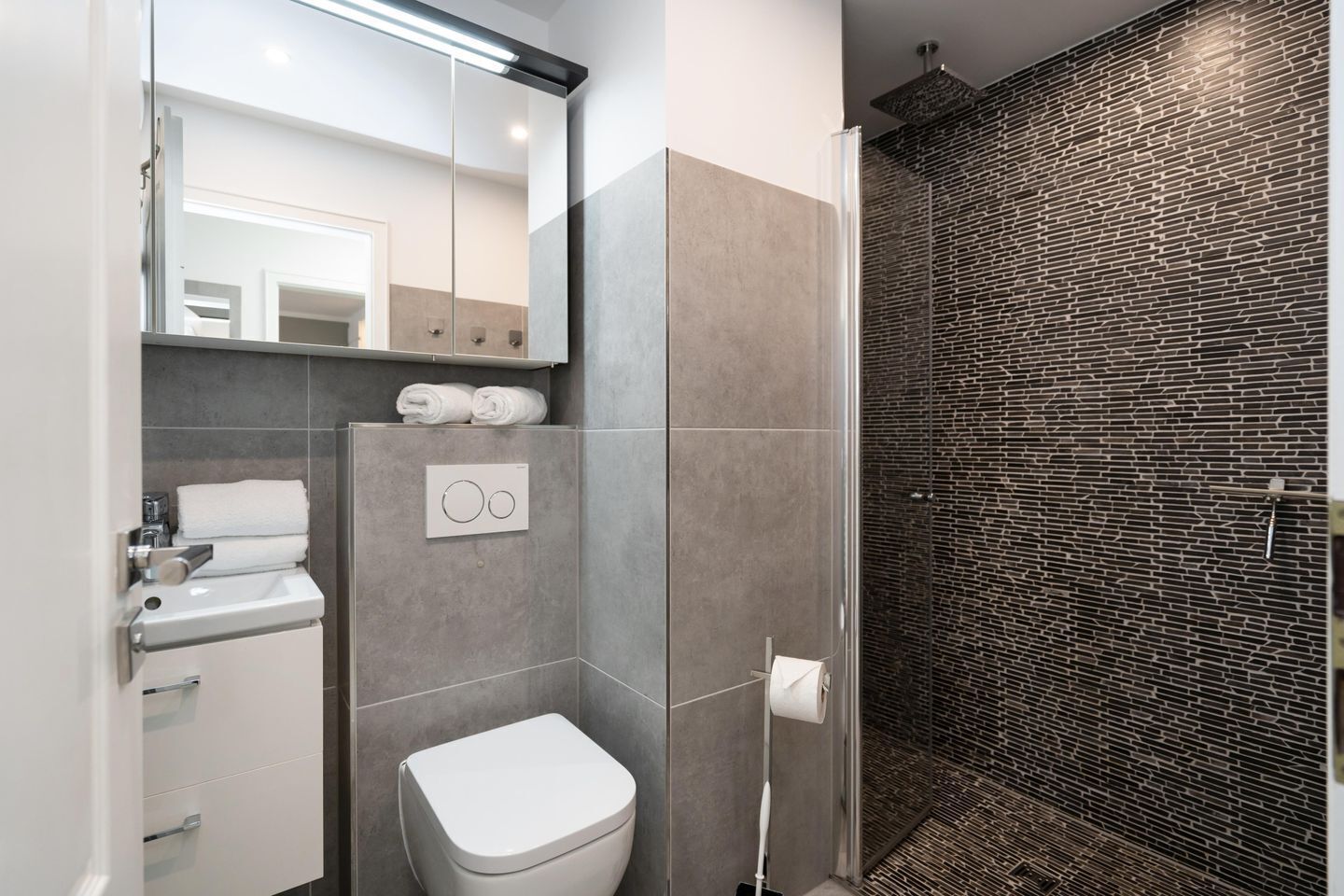 A modern bathroom with a toilet, sink, and shower area.