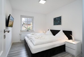 A bedroom with a bed, bedside tables, a window, and artwork on the walls.