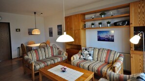 A cozy living room with striped sofas, a wooden coffee table, and pendant lights. - Vacation apartment Warfstr. 3/3 - Wohnpark Werdum (Werdum)