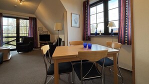 Un comedor con una mesa, sillas, un televisor y una lámpara.