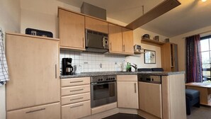 Cocina compacta con armarios de madera, microondas, cafetera y lavabo.