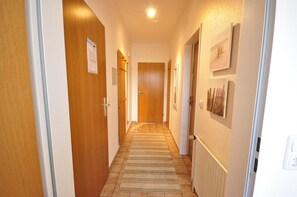 Un pasillo con puertas de madera, piso de baldosas y un radiador en la pared.