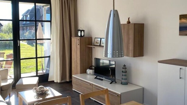 A modern kitchen with a large window, a dining area, and a TV. - "Friesengeist" Werdum - Werdum residential park (Werdum)