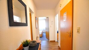 Un couloir avec un banc en bois, une plante en pot et un miroir accroché au mur.