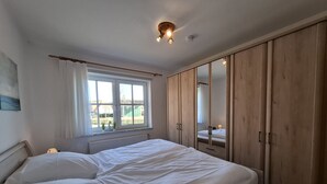 Une chambre à coucher avec un lit, une fenêtre, un radiateur et des armoires en bois.