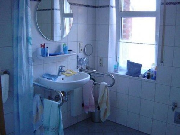Un baño con lavamanos, espejo y ventana.
