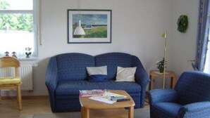 A living room with a blue sofa, a wooden coffee table, and a framed picture on the wall.
