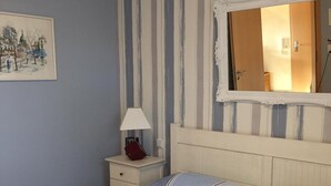 Een slaapkamer met een bed, nachtkastje, lamp en spiegel.