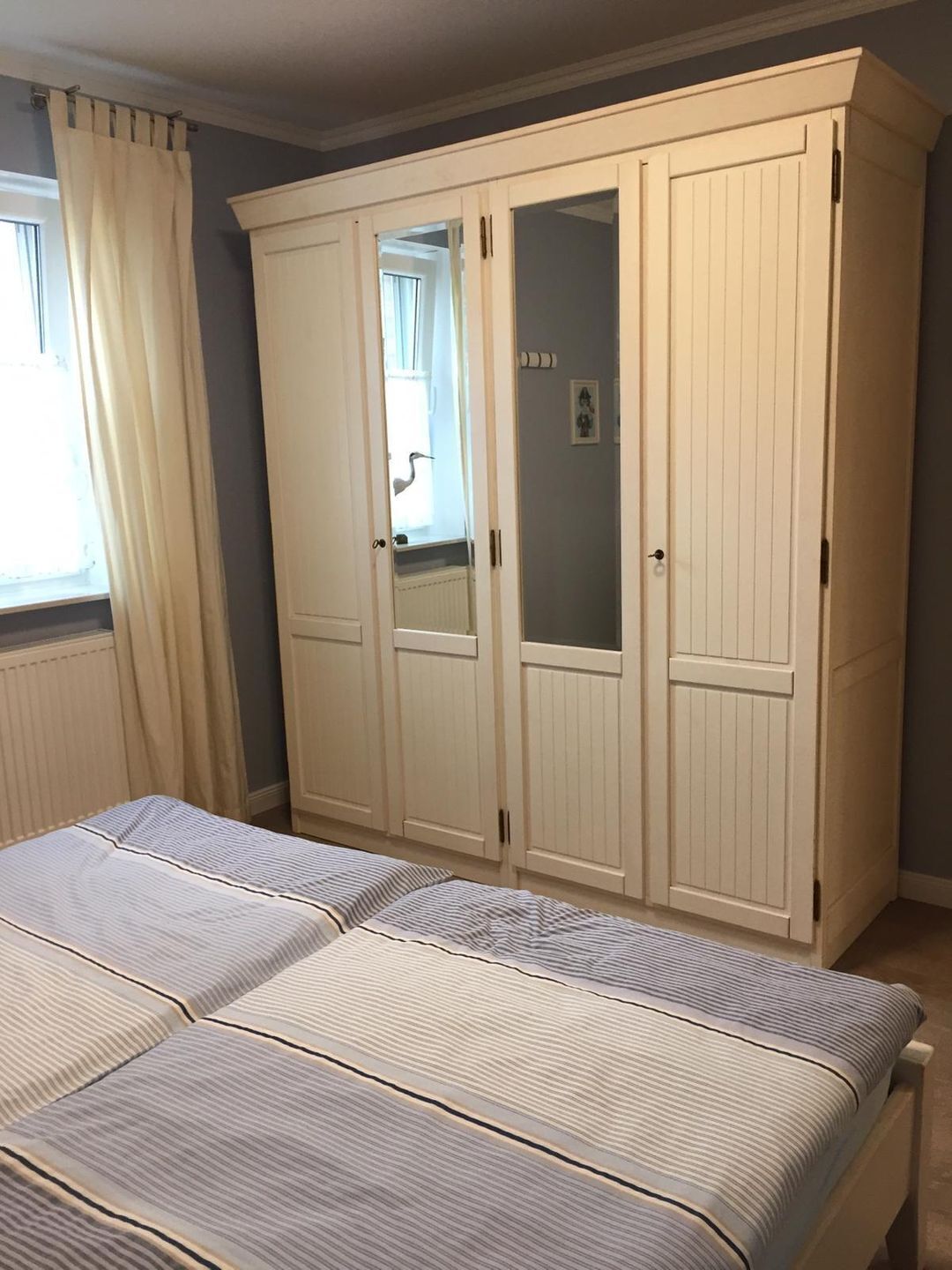 Een slaapkamer met een bed, een kledingkast en een raam met gordijnen.