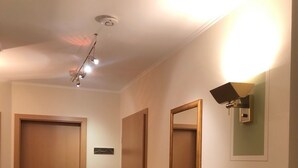 Een gang met een houten kast, een radiator en een plafondlamp.
