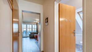 Un pasillo que conduce a una sala de estar con un sofá, una mesita y un ventanal.