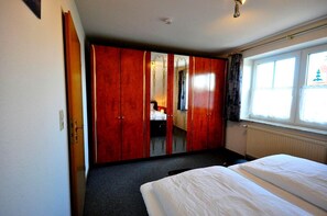 A bedroom with a bed, a wardrobe, and a window.