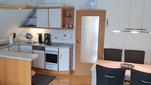 Una cucina compatta con forno a microonde, macchina del caffè e forno. C'è un'area pranzo con tavolo e sedie.