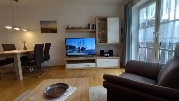 Un soggiorno moderno con zona pranzo, televisione e finestra con tende.