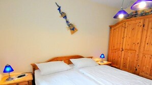 Un dormitorio con una cama de madera, dos lámparas de noche, un armario de madera y un adorno en la pared.