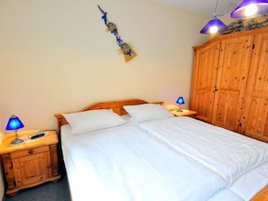 Ein Schlafzimmer mit einem hölzernen Bett, zwei Nachttischlampen, einem Holzschrank und einer Wanddekoration.