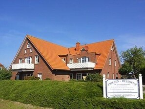 A large, two-story brick building with a red-tiled roof and a sign indicating it is a residence. - Friesenresidenz Vacation Apartment, Apartment No. 5 - Friesenresidenz (Werdum)