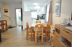 Una cocina moderna con armarios blancos, una mesa de comedor con sillas de madera y una pequeña isla con un lavaplatos.