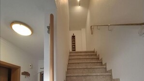 Uma escada com corrimão, uma porta de madeira e um luminário no teto.