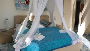 A bed with a canopy, a blue patterned bedspread, and a painting of sailboats on the wall. - Imperiale front beach Apartment  (Viareggio)