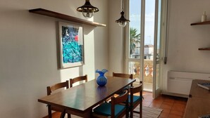 A dining area with a wooden table and chairs, a blue vase, and a painting on the wall. - Imperiale front beach Apartment  (Viareggio)