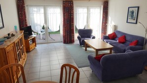 Ein Wohnzimmer mit einer Couch, einem Sessel und einem Fernseher auf einer Holzkommode.